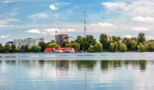Preview: Modern city reflected in a mirror like lake wiht green trees