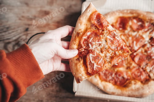 Preview: large slice of pepperoni pizza in hands, close-up. Delicious Italian snack. Pizza with salami.