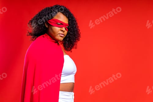 Preview: spanish woman in eye mask and superhero cloak in red studio background