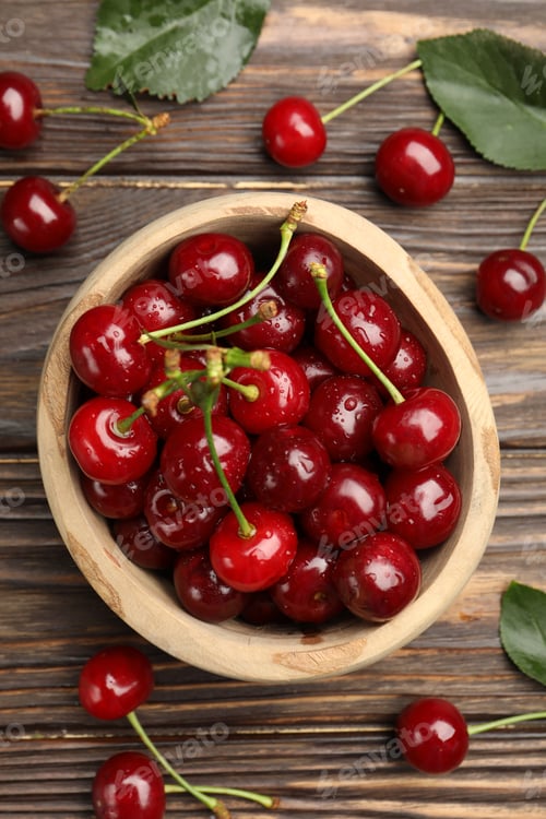 Preview: Fresh wet cherries in bowl and leaves on wooden table, flat lay