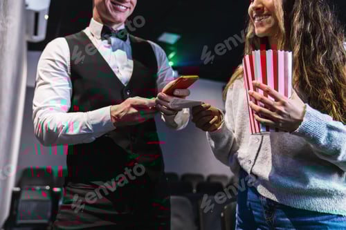 Preview: Usher checking tickets and using smartphone at movie theater