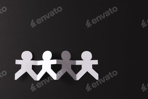 Preview: Close up of four paper cut out people figures holding hands with copy space on black background