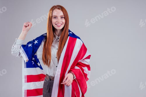 Preview: happy young and beautiful redheaded businesswoman holding American flag