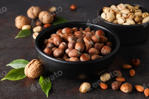 Preview: Different types of nuts in black bowls on a dark background