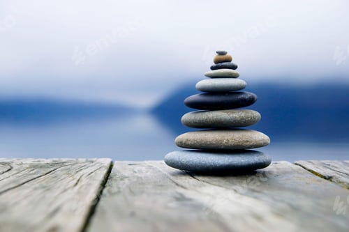Preview: Zen balancing pebbles next to a misty lake.