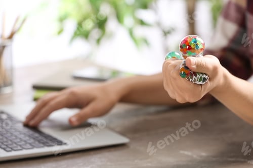 Preview: Woman squeezing colorful slime in office, closeup. Antistress toy