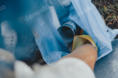 Preview: Female collecting the trash and putting in a plastic garbage bag - environmental pollution concept