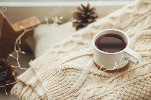 Preview: Cozy winter still life. Stylish cup of tea with cozy knitted sweater, pine cone