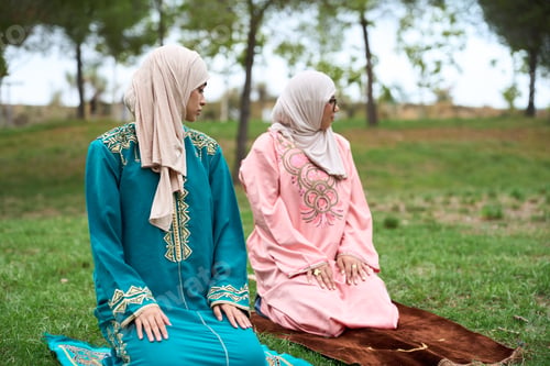 Preview: Muslim women praying outdoors on prayer mats
