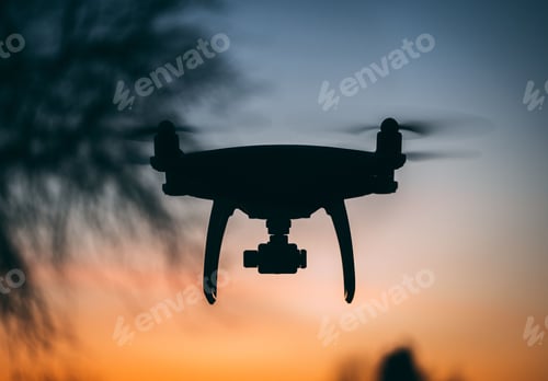 Preview: silhouette of a drone flying towards the sunset with the camera pointed in