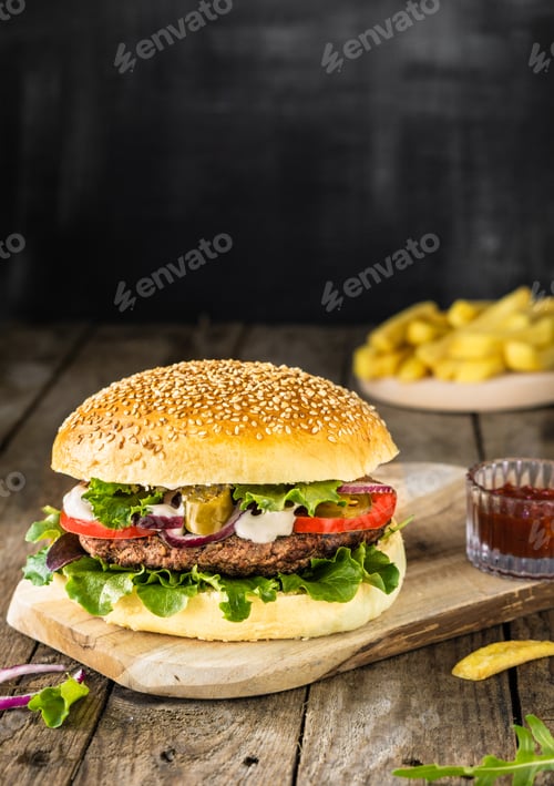 Preview: Beef burger with salad tomato onion jalapenos and fresh fries over brown wood background