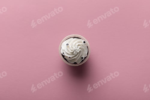 Preview: top view of delicious Halloween cupcake with white cream on pink background