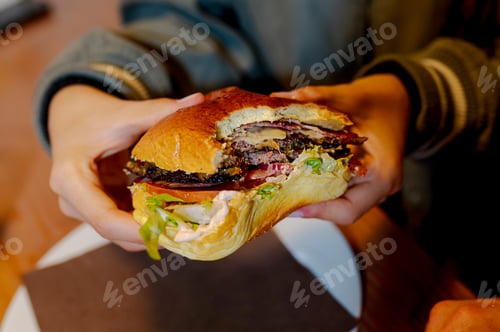 Preview: Customer holding a delicious burger in fast food restaurant