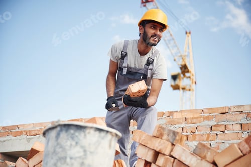 Preview: Blue sky and crane is behind. Handsome Indian man is on the construction site