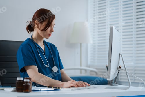 Preview: Doctor working with laptop computer and writing on paperwork.
