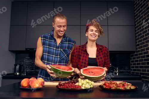 Preview: Happy couple standing in kitchen at home preparing together yummy dinner on first dating, spouses