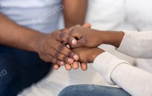 Preview: Romantic black couple holding hands, sitting at home together