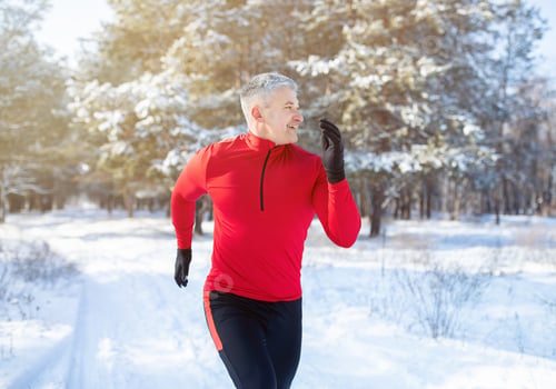 Preview: Mature trail runner training for marathon in beautiful snowy forest. Outdoor seasonal sports concept
