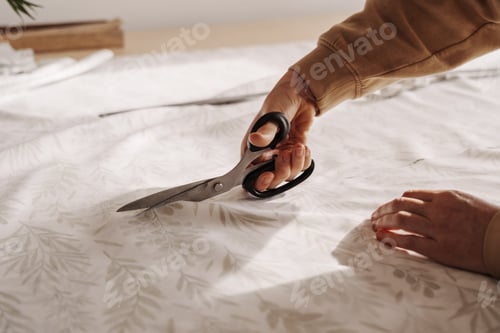 Preview: Skilled seamstress cutting fabric in sunlit sewing workshop