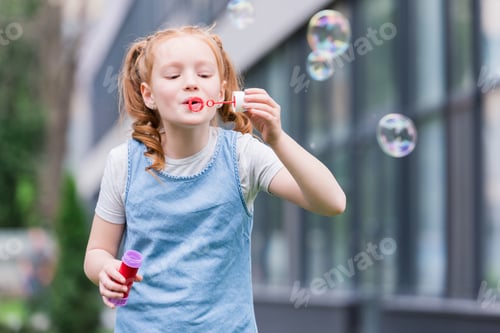 Preview: portrait of cute child blowing soap bubbles on street