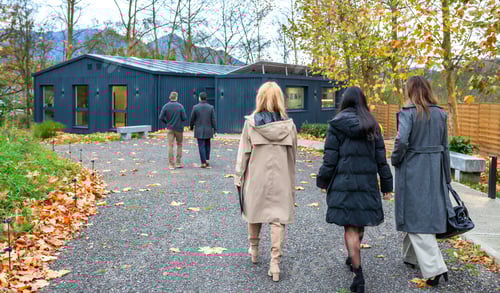 Preview: Business professionals team walking to eco friendly home building made with shipping containers