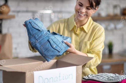 Preview: Happy lady packing her clothes for donation