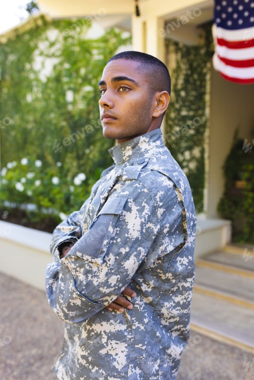 Preview: Biracial male american soldier wearing military uniform standing outside the house and looking away