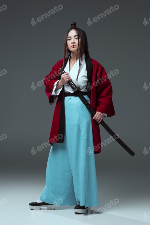Preview: samurai in kimono holding katana sword and looking at camera on grey