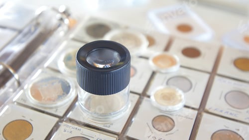 Preview: Round magnifying glass on album with coins from different countries - Numismatic scene