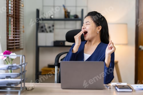 Preview: Asian businesswoman yawning while working on a laptop computer at the office woman in financial mana