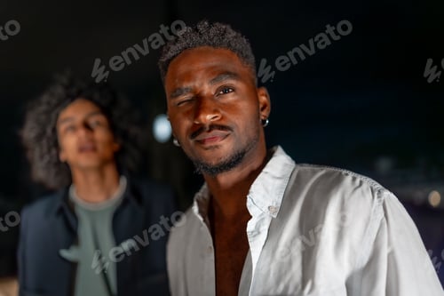 Preview: Man in white t-shirt looking at camera during night party