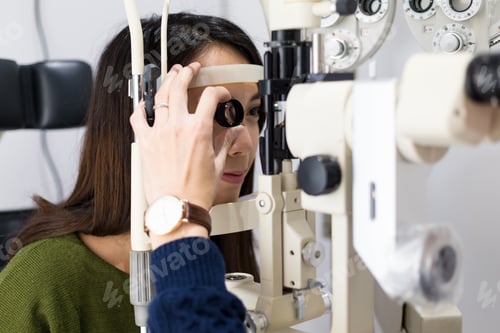 Preview: Woman checking vision with tonometer at eye clinic