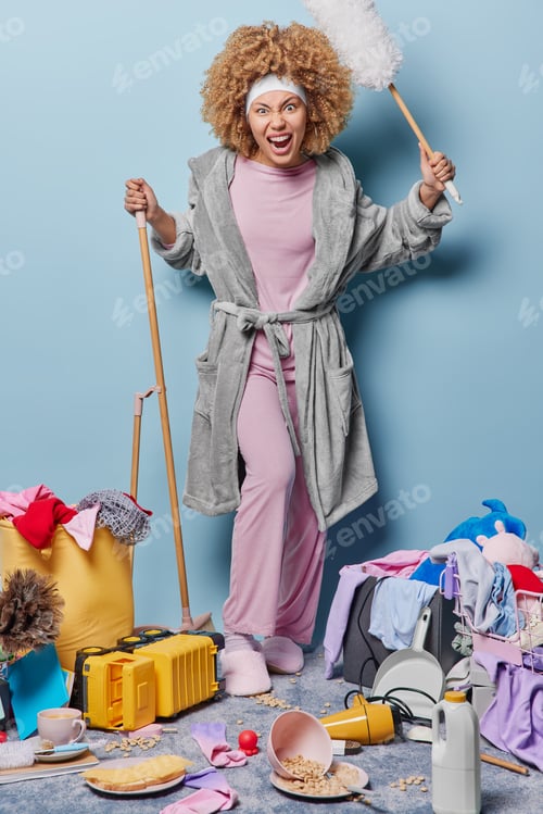 Preview: Angry housewife dressed in domestic clothes screams loudly holds broom and brush sweeps floor and