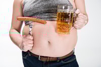 Vorschau: abgeschnittene Ansicht eines übergewichtigen Mannes, der Bauch zeigt und ein Glas Bier mit Grillwurst hält, isoliert