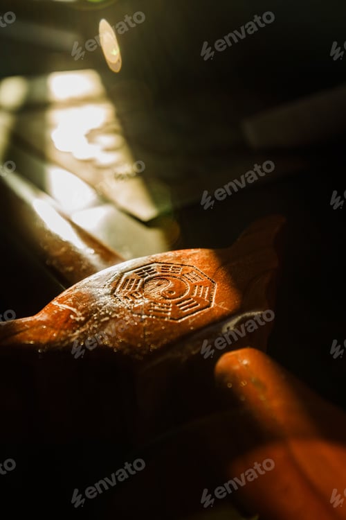 Preview: Closeup picture of sunshine shining on a wooden sword with the yin and yang symbol on the handle