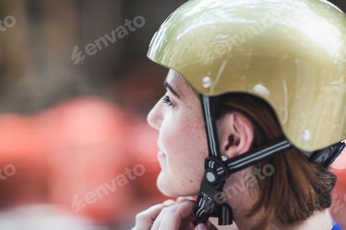 Preview: Close up of mid adult woman cyclist fastening cycle helmet