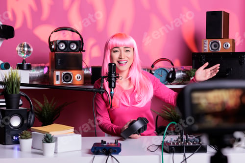 Preview: Smiling asian vlogger with pink hair talking with subscribers while filming vlog using recording