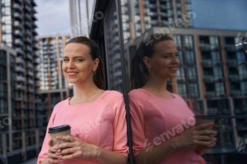 Preview: Beautiful woman in cute dress is standing on terrace with coffee
