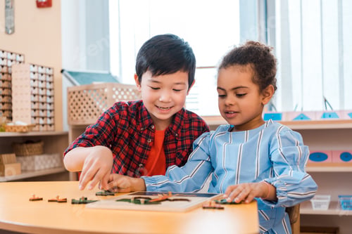 Preview: Children playing with wooden board game at table in montessori class