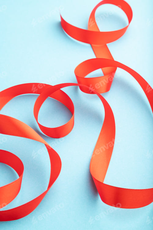 Preview: Red ribbon on a blue pastel background. Side view, copy space.