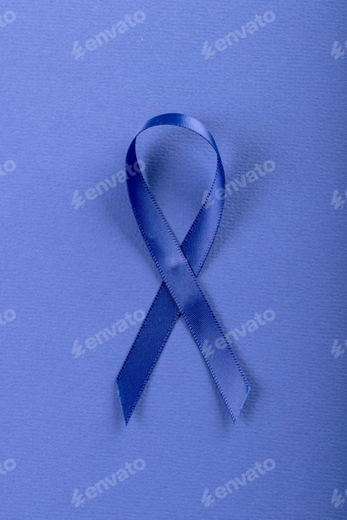 Preview: Close-up of blue stomach cancer awareness ribbon isolated against blue background, copy space