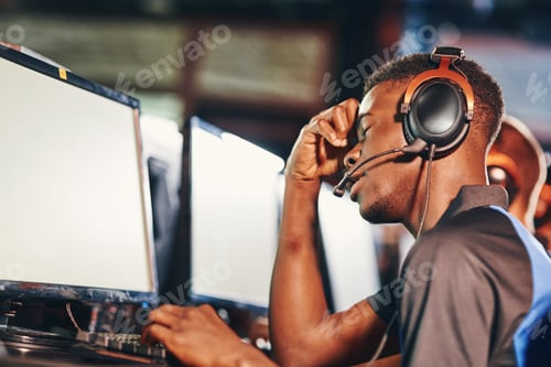 Preview: Side view of upset african guy, professional cybersport gamer looking at PC