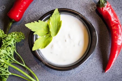 Preview: Overhead shot of a white soup with a vegetable leaf on top in a black bowl
