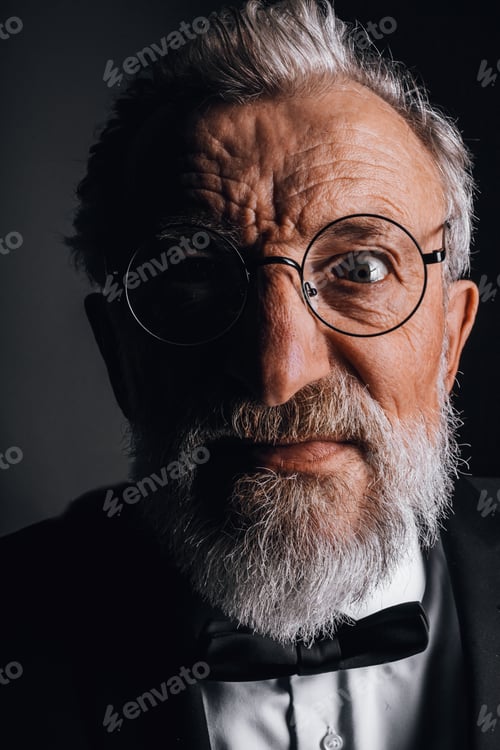 Preview: face of elderly man in suit with bow tie gazes at camera with crazy stunned look