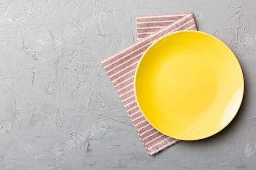 Preview: Top view on colored background empty round yellow plate on tablecloth for food.