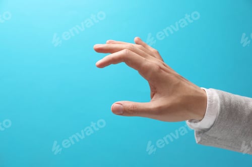 Preview: Man holding something in hand on light blue background, closeup. Space for text