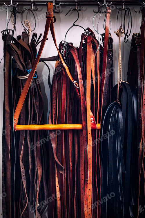 Preview: An array of leather belts hanging on a rack.