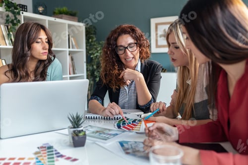 Preview: Group of multiage designer women working in a design project while choosing materials in the office.