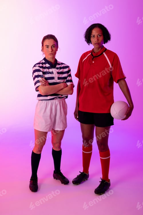 Preview: Portrait of two diverse female rugby players with rugby ball over neon pink lighting