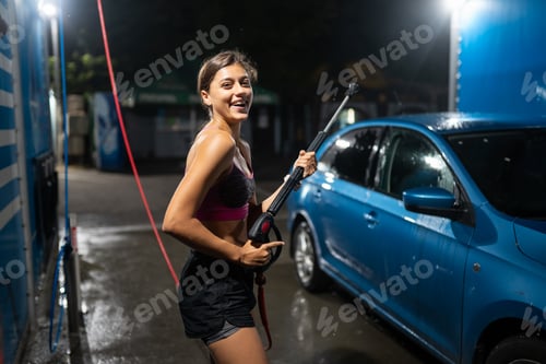 Preview: Young woman washing blue car at car wash